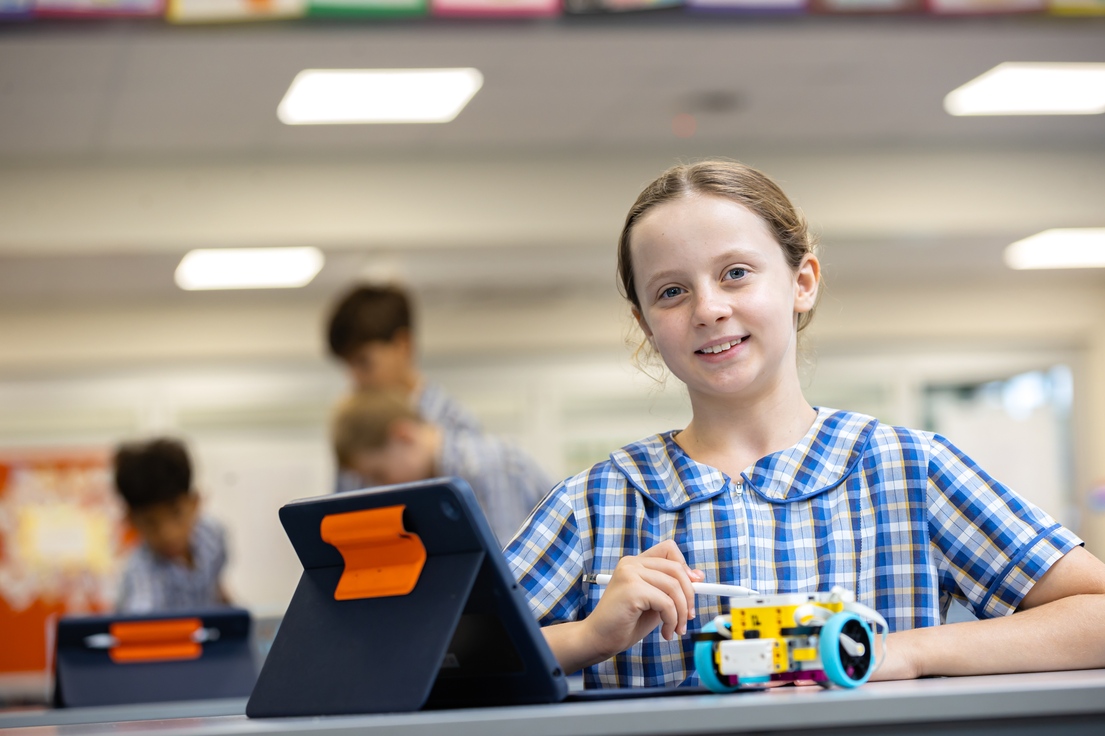 Student using a tablet and small robotics kit during a hands‑on STEM learning activity in a classroom